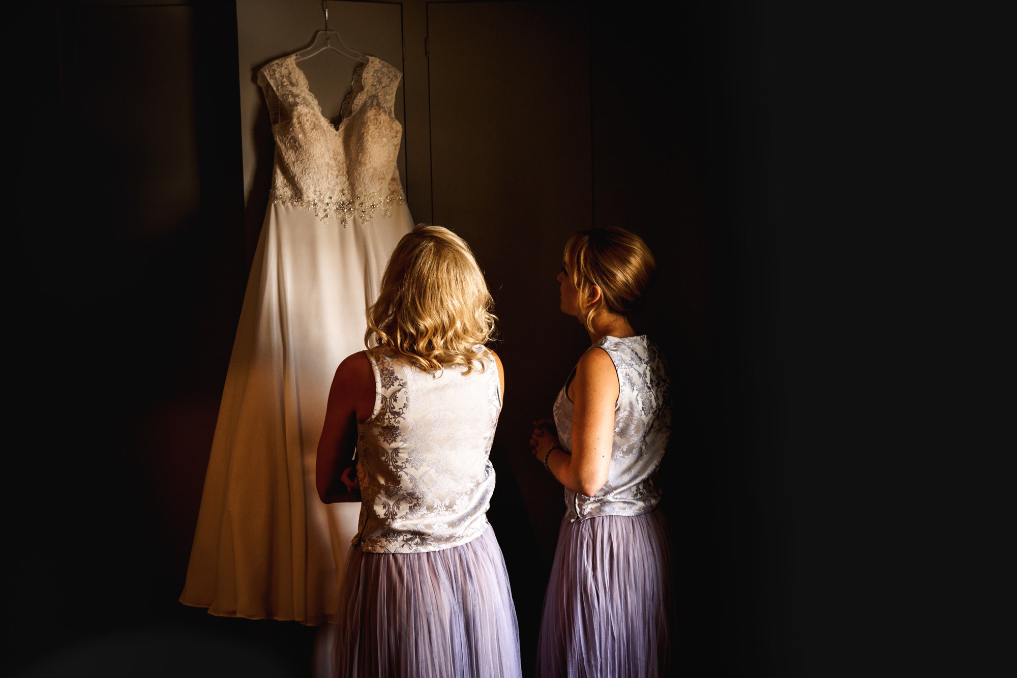 bridesmaids look at wedding dress