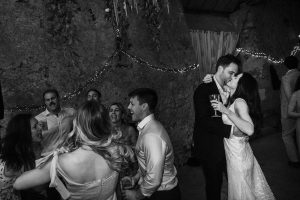Bride and groom kiss while holding champagne at their wedding reception.